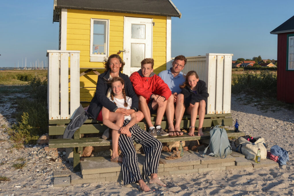 Familienfoto vor einem Badehaus am Strand.