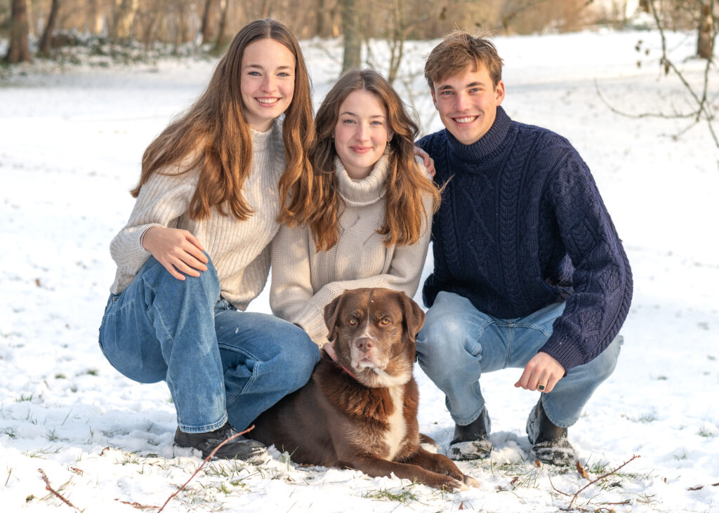 Drei Kinder Familienfoto mit Hund im Schnee.