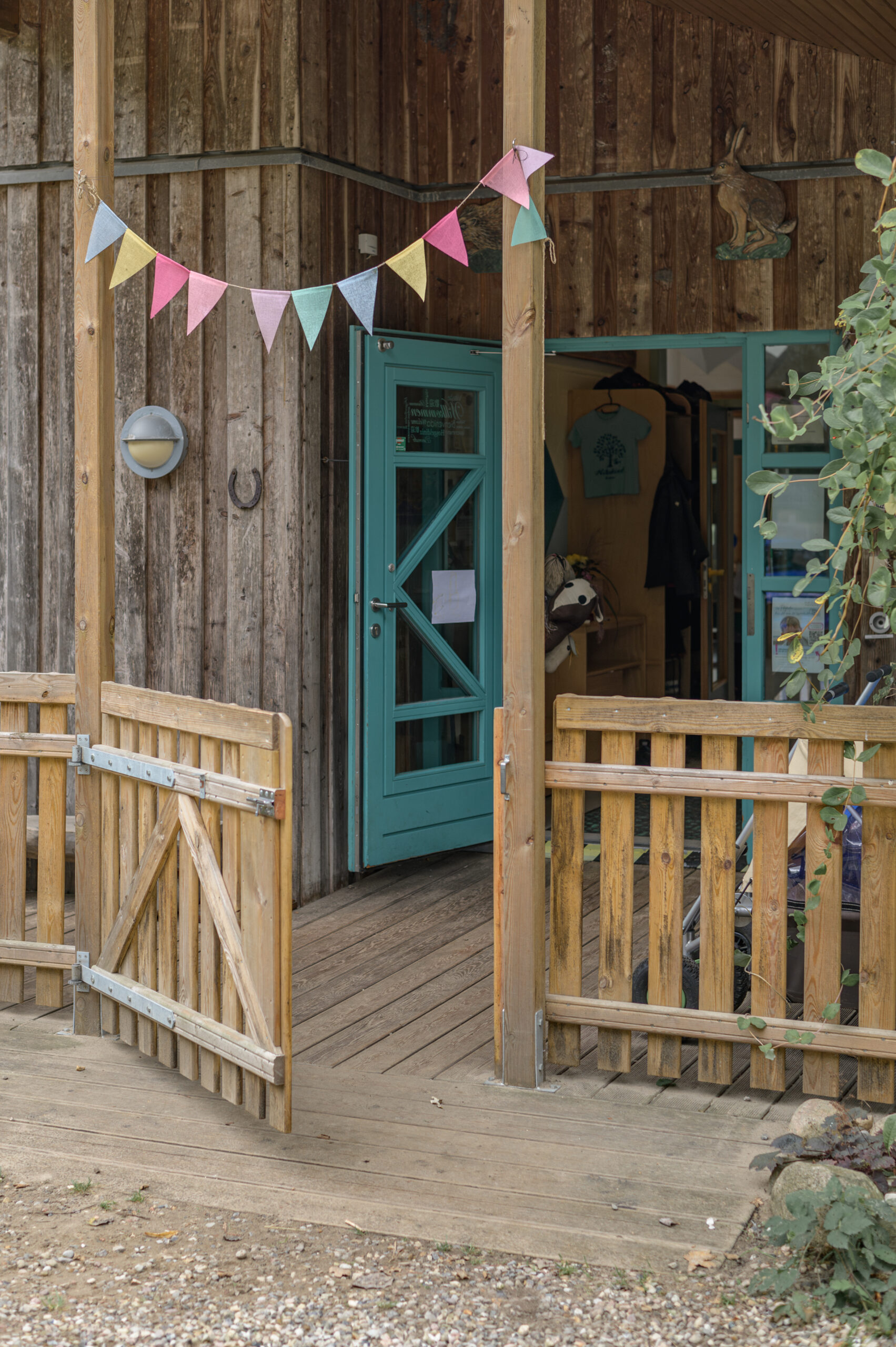 Eingang der ADS Natur-Kita in Oeversee mit viel Holz und einer bunten Girlande am Fototag mit Annette Kleinschmidt Kitafotografin in Gluecksburg, Flensburg und Umgebung.