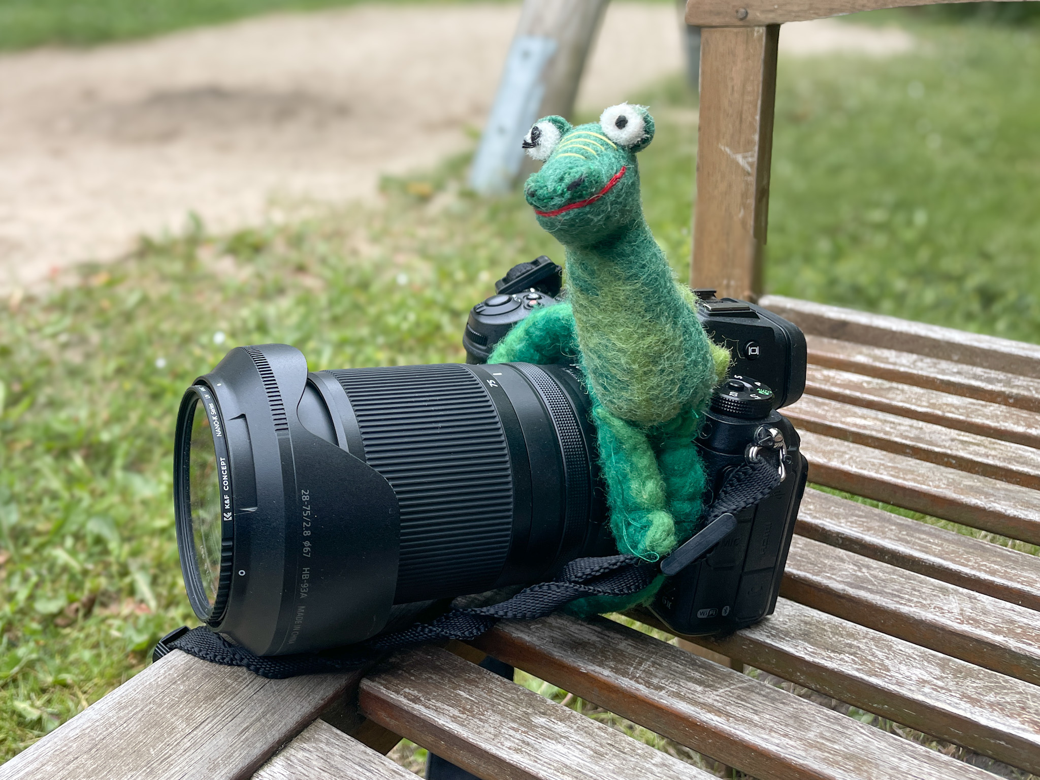 Kamera Nikon Z6II mit einem Krokodil als Kameratier um das Objektiv auf einer hoelzernen Bank im Aussenbereich des Kindergartens in Maasbuell am Fototag mit Annette Kleinschmidt, der Kitafotografin aus Gluecksburg