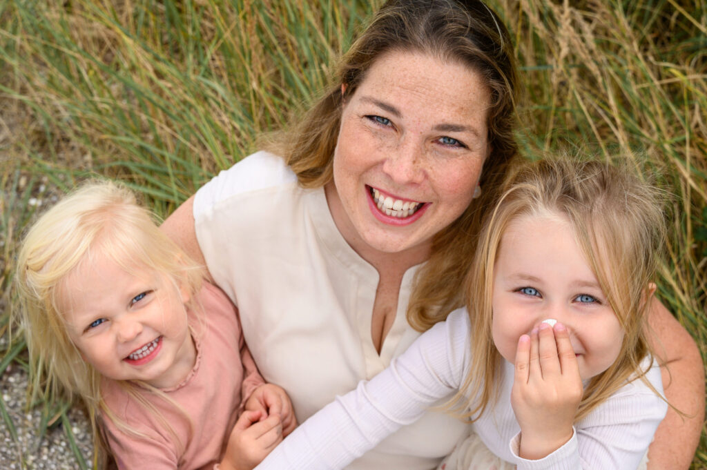 Mutter hat ihre Toechter im Arm und alle drei schauen nach oben in die Kamera
