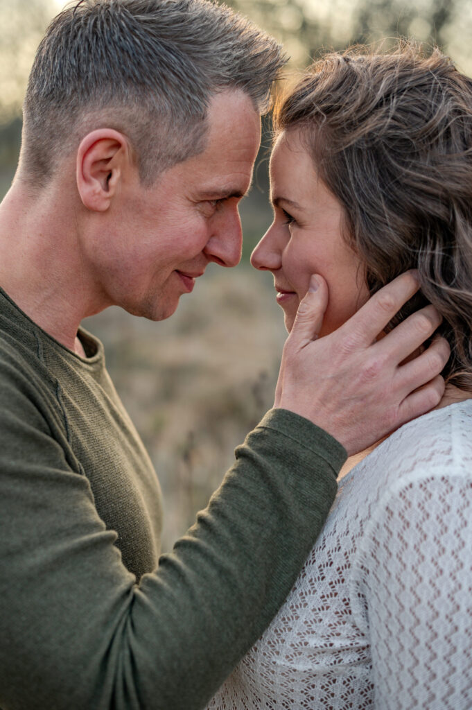 sehr enger Blickkontakt des Paares als Zeichen der Verbundenheit und Nähe diem Foto Shooting in Flensburg. Die Nasenspitzen berühren such fasst und seine Hand beruehrt liebevoll ihre Wange im Abendlicht in Flensburg.