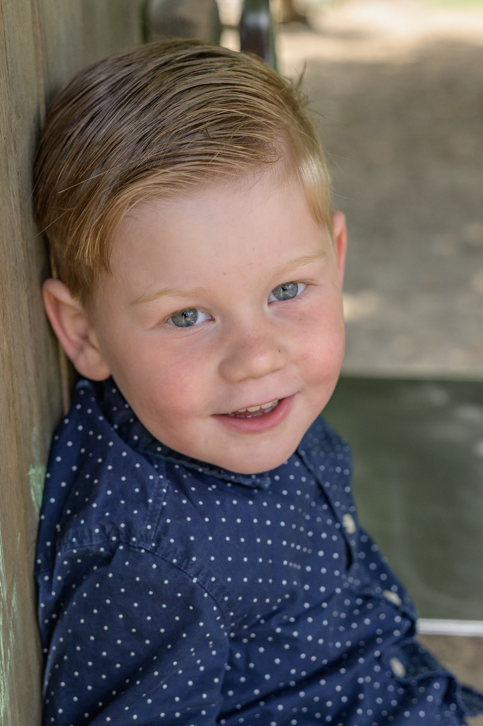Kita Junge sitzt oben vor der Rutsche und unterhält sich fröhlich mit Annette Kleinschmidt, der Fotografin.