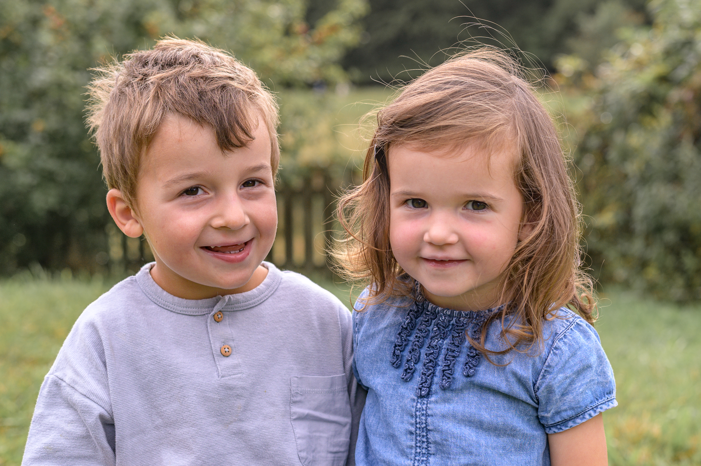 natürliches Porträtfoto von Geschwisterkindern im Garten des Kindergartens in Flensburg.