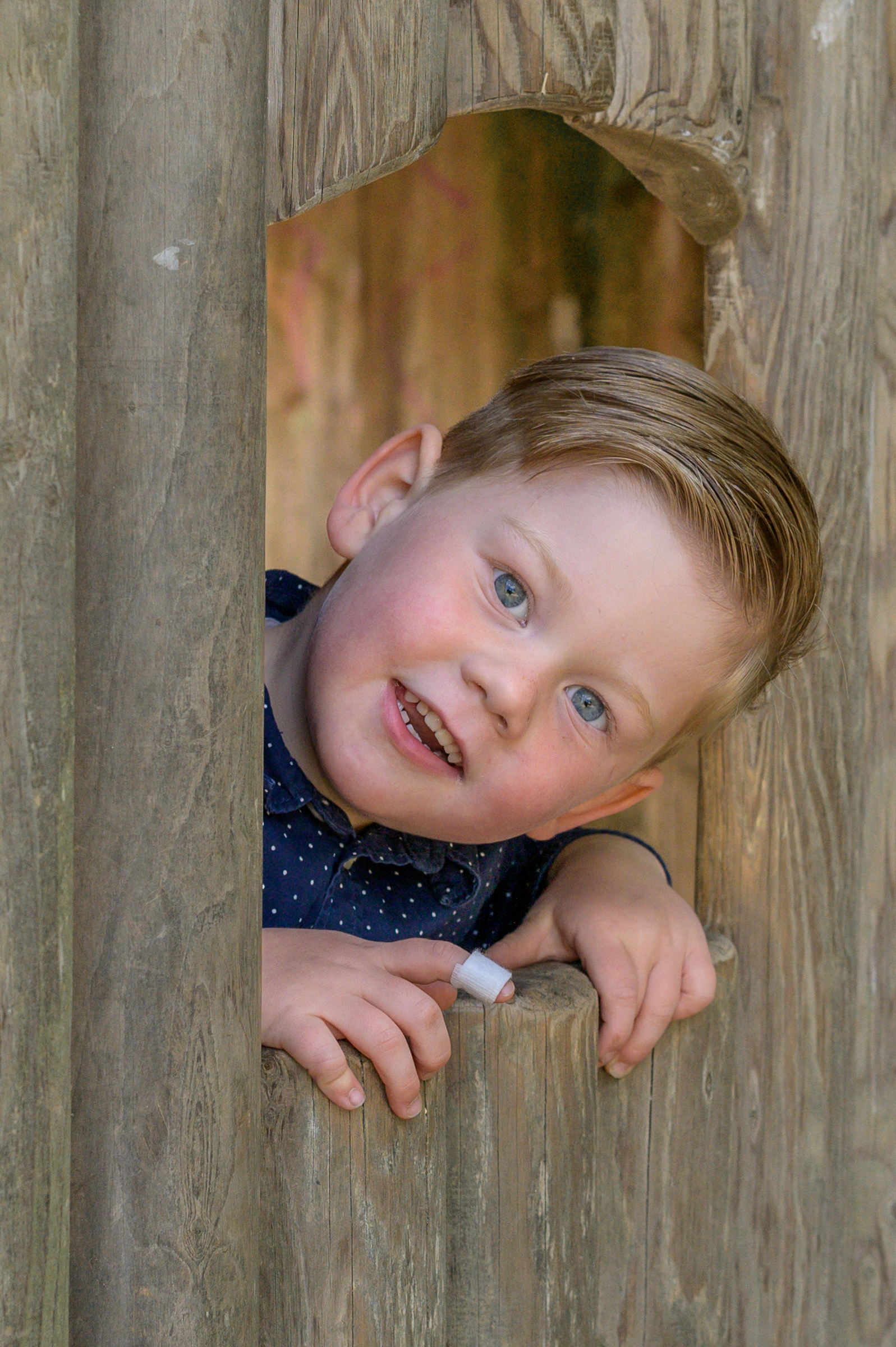 Flensburger Kita Junge schaut aus dem Fenster des Spielhauses und hat Spass mit der Fotografi Annette Kleinschmidt.